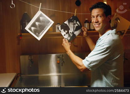 Portrait of a mature man holding photographs in a dark room