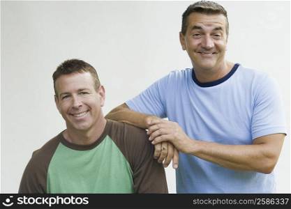 Portrait of a mature man leaning on his brother&acute;s shoulder and smiling