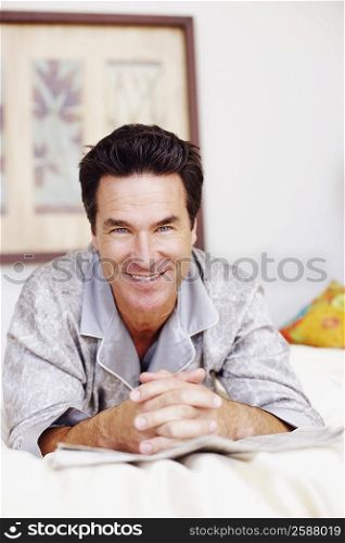 Portrait of a mature man lying on the bed and smiling
