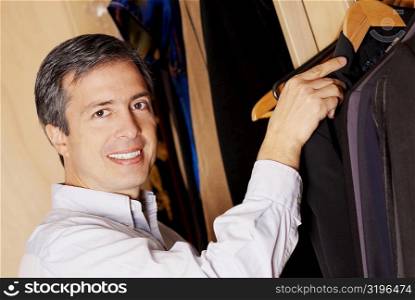 Portrait of a mature man picking a coat from a closet