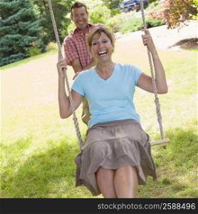 Portrait of a mature man pushing a mature woman on a rope swing