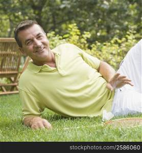 Portrait of a mature man reclining on grass with a badminton racket and a shuttlecock