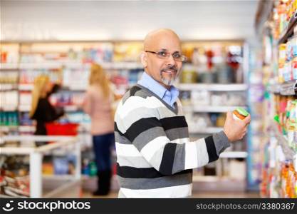 Portrait of a mature man shopping in the supermarket with people in the background