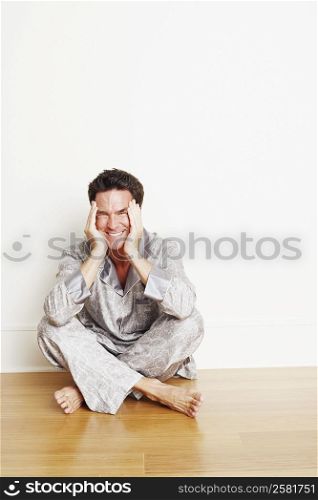 Portrait of a mature man sitting cross-legged on the floor and making a face