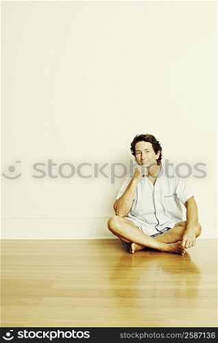 Portrait of a mature man sitting cross-legged on the floor and thinking