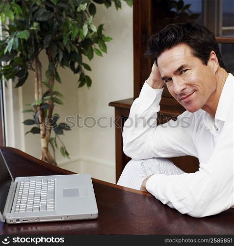 Portrait of a mature man sitting in front of a laptop