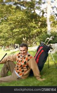 Portrait of a mature man sitting near a golf bag