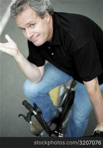 Portrait of a mature man sitting on a bicycle and gesturing