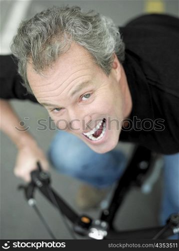 Portrait of a mature man sitting on a bicycle and laughing