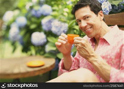 Portrait of a mature man sitting on a chair and drinking a cup of tea