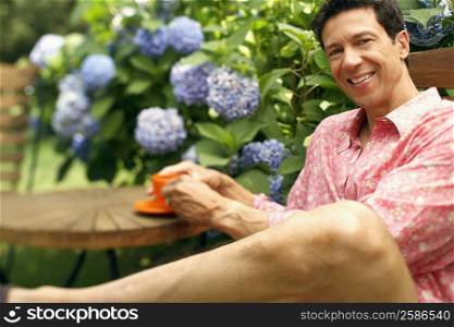 Portrait of a mature man sitting on a chair and holding a cup of tea