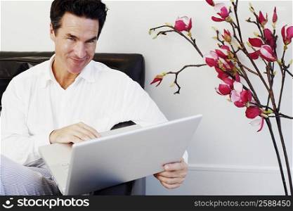 Portrait of a mature man sitting on a couch and using a laptop