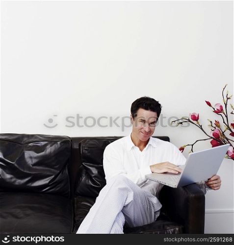Portrait of a mature man sitting on a couch and using a laptop