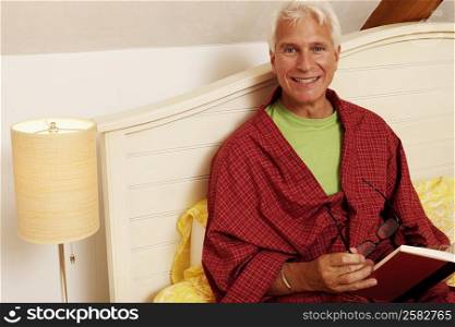 Portrait of a mature man sitting on the bed and smiling