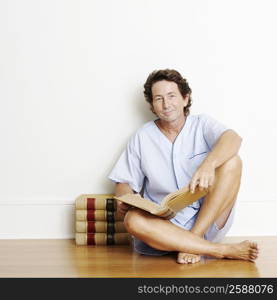 Portrait of a mature man sitting on the floor and holding a book