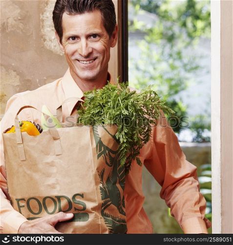 Portrait of a mature man smiling and holding a shopping bag