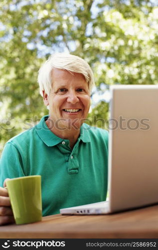 Portrait of a mature man smiling with a laptop in front of him