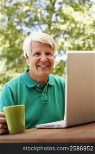 Portrait of a mature man smiling with a laptop in front of him