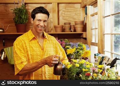 Portrait of a mature man spraying water over potted plants