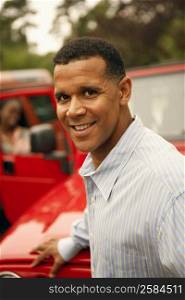 Portrait of a mature man standing near a car and smiling