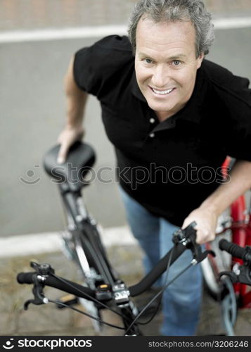 Portrait of a mature man standing with a bicycle and smiling