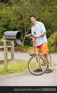 Portrait of a mature man standing with a bicycle near a mailbox