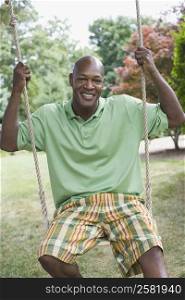 Portrait of a mature man swinging on a rope swing