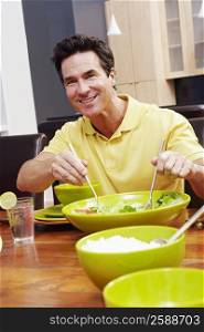 Portrait of a mature man taking salad from a bowl