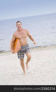 Portrait of a mature man walking with a surfboard on the beach and smiling