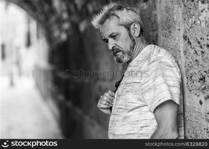 Portrait of a mature man with grey hair in urban background. Senior male with white hair and beard wearing casual clothes.