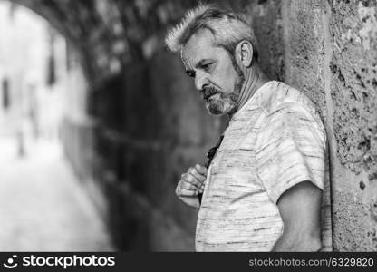 Portrait of a mature man with grey hair in urban background. Senior male with white hair and beard wearing casual clothes.