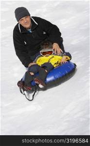 Portrait of a mature man with his daughter sitting in an inflatable ring