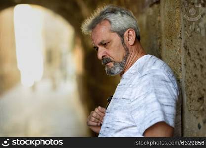 Portrait of a mature serious man in urban background. Senior male with white hair and beard wearing casual clothes.