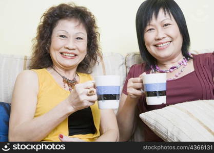 Portrait of a mature woman and a senior woman holding cups and smiling