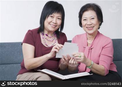Portrait of a mature woman and a senior woman holding photographs and smiling