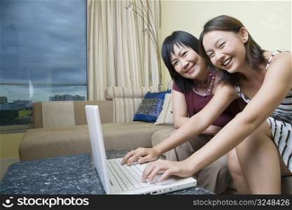 Portrait of a mature woman and her daughter using a laptop and smiling