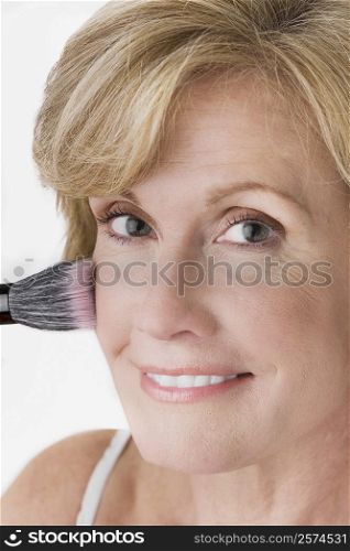 Portrait of a mature woman applying blush on her face