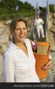 Portrait of a mature woman carrying a beach mat and smiling on the beach