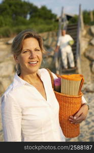 Portrait of a mature woman carrying a beach mat and smiling on the beach