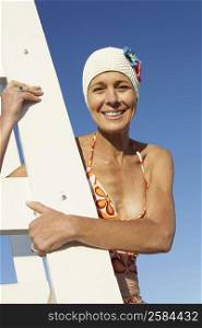 Portrait of a mature woman climbing a lifeguard chair and smiling