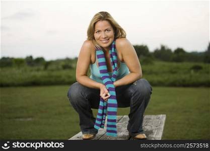 Portrait of a mature woman crouching on a picnic table