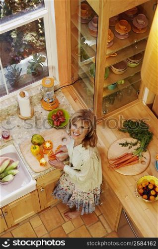 Portrait of a mature woman cutting vegetables in the kitchen