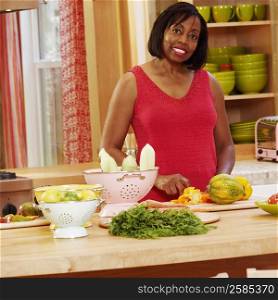 Portrait of a mature woman cutting vegetables in the kitchen and smiling
