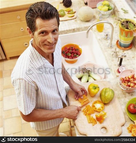 Portrait of a mature woman cutting yellow bell peppers in the kitchen