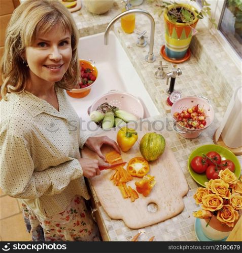 Portrait of a mature woman cutting yellow bell peppers in the kitchen