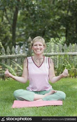 Portrait of a mature woman doing yoga in a lawn and smiling