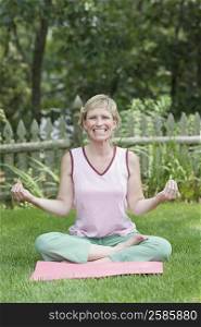 Portrait of a mature woman doing yoga in a lawn and smiling