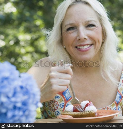 Portrait of a mature woman eating a fruit tart
