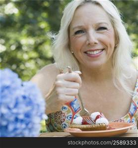 Portrait of a mature woman eating a fruit tart