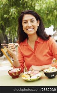Portrait of a mature woman eating with chopsticks